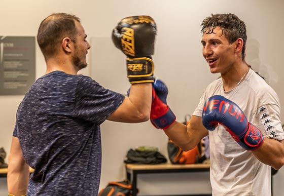 Deux boxeurs en plein entraînement échangent des coups avec des gants de boxe colorés.