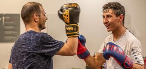 Deux boxeurs en plein entraînement échangent des coups avec des gants de boxe colorés.