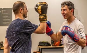 Deux boxeurs en plein entraînement échangent des coups avec des gants de boxe colorés.